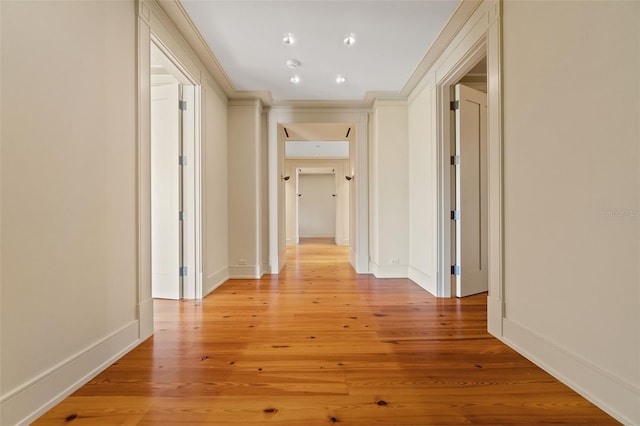 hallway with light hardwood / wood-style floors and ornamental molding