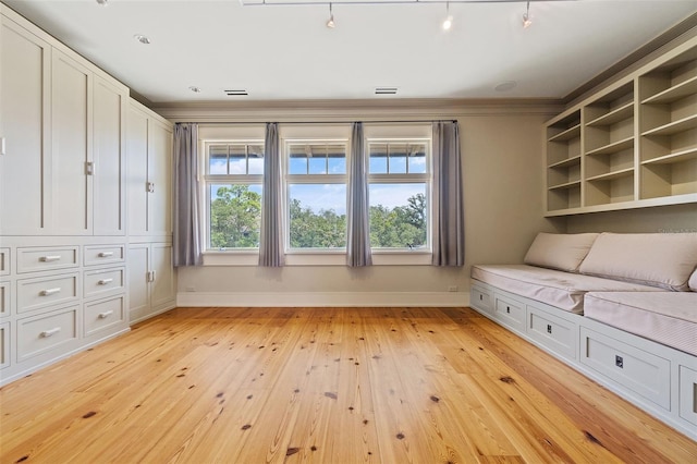 unfurnished room with track lighting, light wood-type flooring, crown molding, and a wealth of natural light