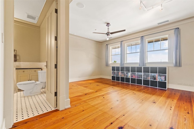 spare room featuring rail lighting, crown molding, light hardwood / wood-style flooring, and ceiling fan