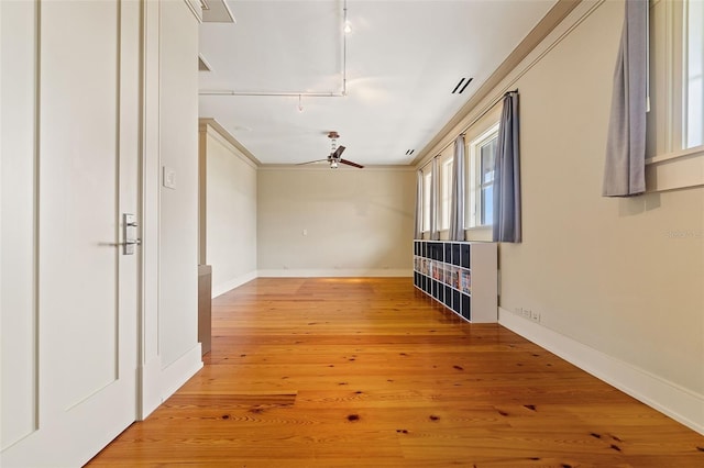 spare room with wood-type flooring, ceiling fan, crown molding, and track lighting