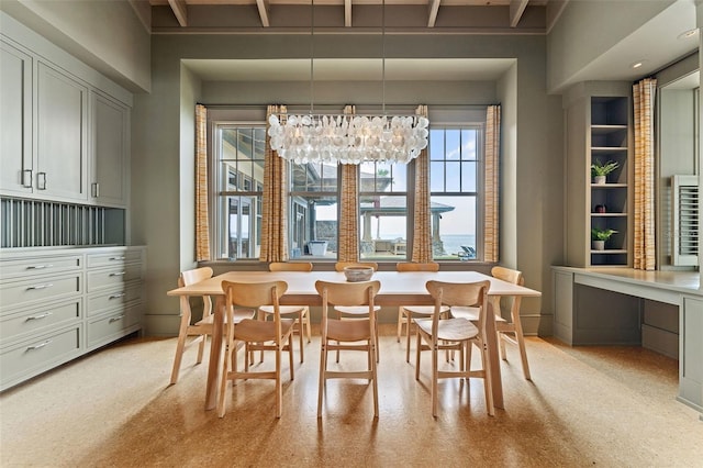 dining space featuring beam ceiling, an inviting chandelier, and built in desk