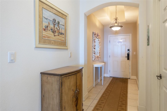 entryway featuring light tile patterned floors, baseboards, and arched walkways