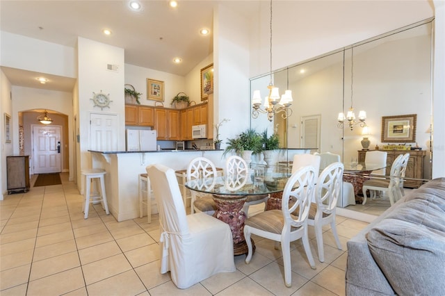 dining area with high vaulted ceiling, a notable chandelier, and light tile patterned flooring