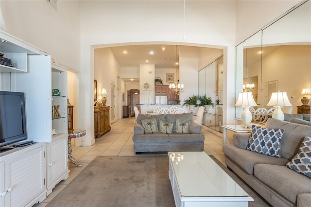 living room with a towering ceiling, a chandelier, and light tile patterned flooring