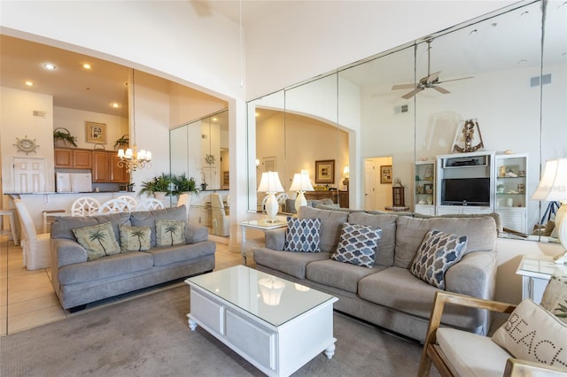 living room featuring ceiling fan with notable chandelier, light tile patterned flooring, and a towering ceiling