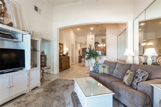 living area featuring a chandelier, light tile patterned floors, a high ceiling, and visible vents