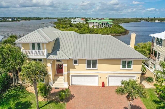 view of front of property featuring a garage, a balcony, and a water view