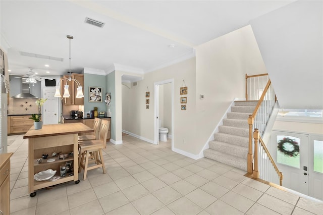 interior space featuring ceiling fan, light tile floors, and crown molding