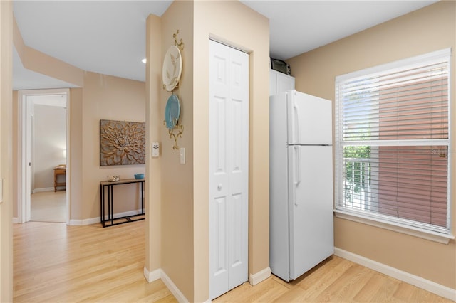 kitchen with white refrigerator, white cabinets, and light hardwood / wood-style flooring