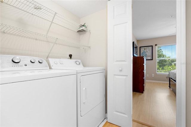 clothes washing area featuring independent washer and dryer and light hardwood / wood-style floors