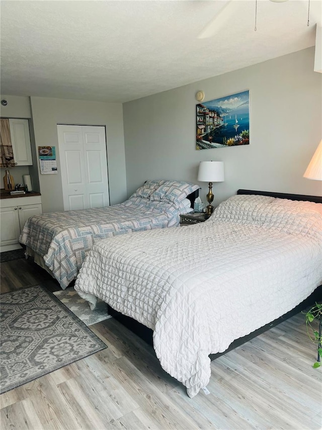 bedroom with a closet, light hardwood / wood-style floors, ceiling fan, and sink