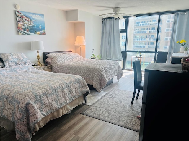 bedroom featuring expansive windows, ceiling fan, and light hardwood / wood-style flooring