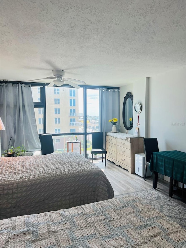 bedroom featuring light hardwood / wood-style floors, ceiling fan, and a textured ceiling