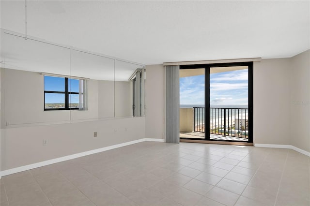 unfurnished room with a healthy amount of sunlight, light tile patterned flooring, floor to ceiling windows, and a water view