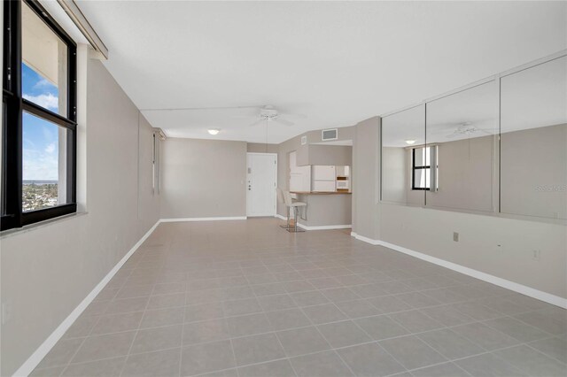 empty room with ceiling fan and light tile patterned floors