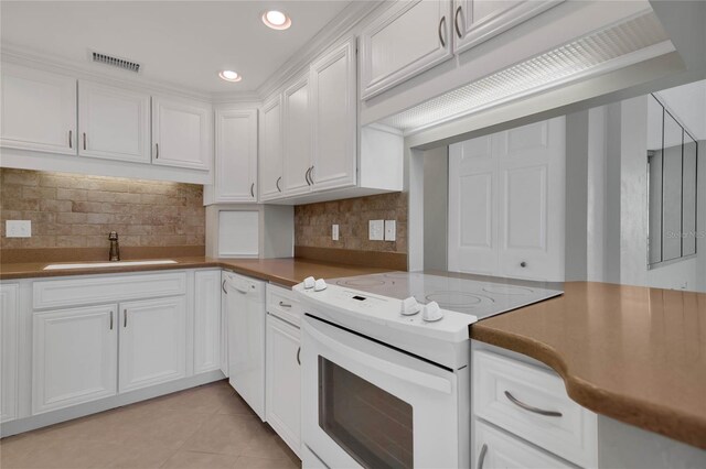 kitchen featuring white appliances, white cabinets, sink, decorative backsplash, and light tile patterned floors