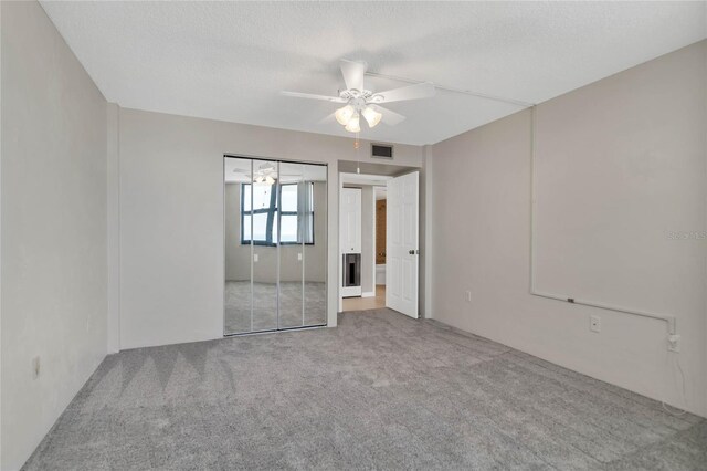 carpeted empty room with ceiling fan and a textured ceiling