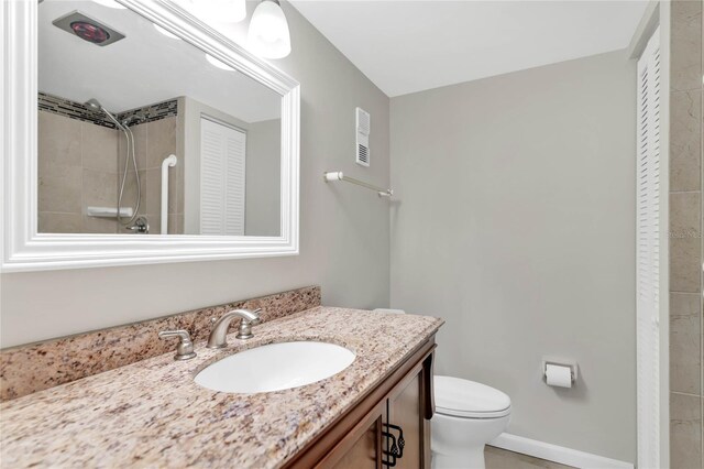 bathroom with a tile shower, vanity, and toilet