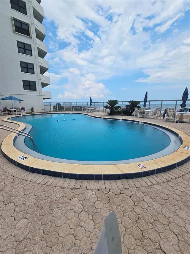 view of swimming pool featuring a patio area and a water view