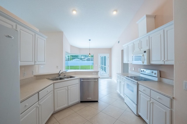 kitchen with vaulted ceiling, decorative light fixtures, white appliances, sink, and white cabinets