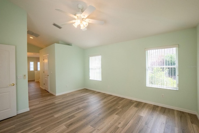 empty room featuring lofted ceiling, light hardwood / wood-style flooring, ceiling fan, and a wealth of natural light