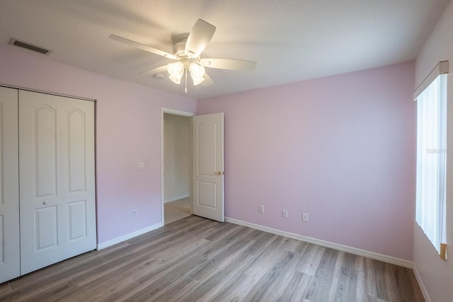 unfurnished bedroom with multiple windows, a closet, ceiling fan, and light hardwood / wood-style floors