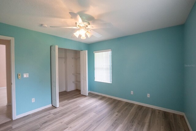 unfurnished bedroom with ceiling fan, a closet, and light wood-type flooring