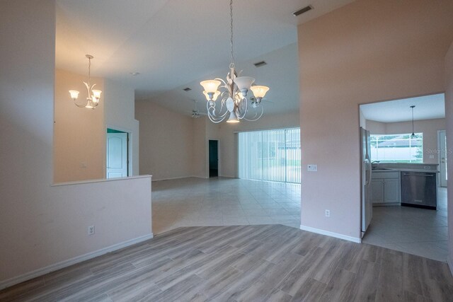 empty room with high vaulted ceiling, light hardwood / wood-style flooring, and an inviting chandelier