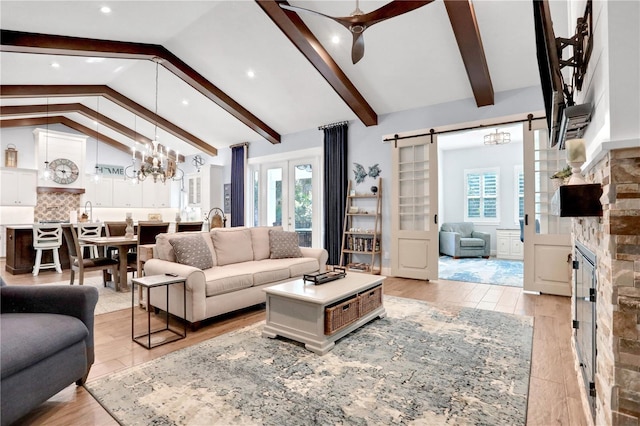 living room featuring light wood-type flooring, beam ceiling, a barn door, and high vaulted ceiling