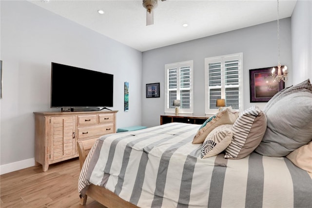 bedroom with ceiling fan with notable chandelier and light hardwood / wood-style flooring