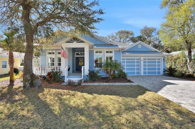 view of front facade featuring covered porch, a front yard, and a garage