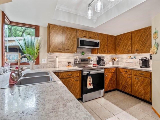 kitchen with sink, crown molding, backsplash, stainless steel appliances, and a tray ceiling