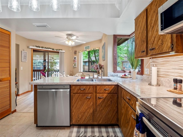 kitchen with ceiling fan, sink, light tile floors, hanging light fixtures, and stainless steel appliances