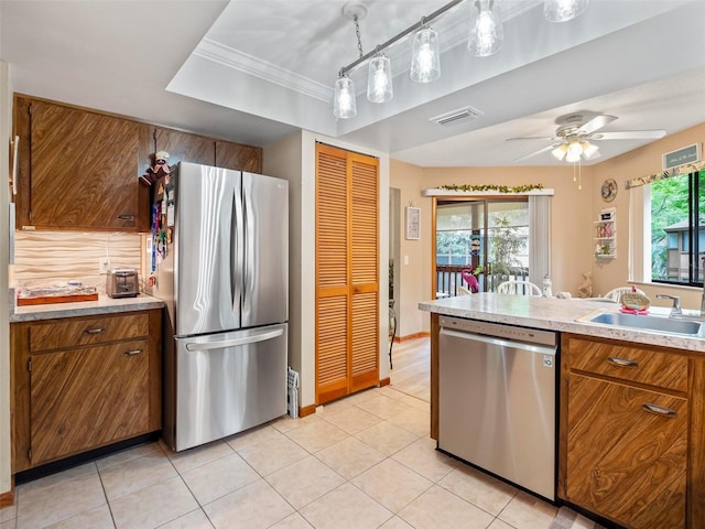 kitchen featuring ceiling fan, sink, stainless steel appliances, crown molding, and pendant lighting