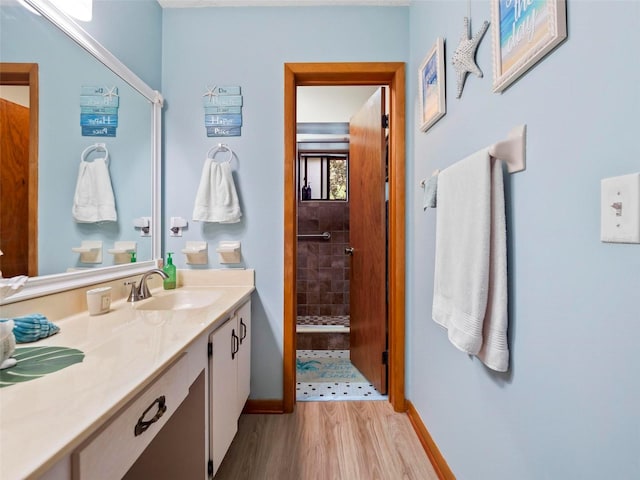 bathroom featuring hardwood / wood-style floors, a tile shower, and oversized vanity