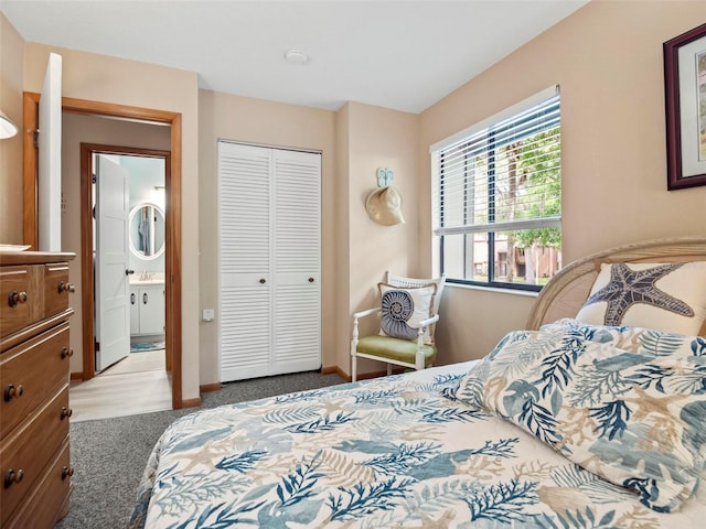 bedroom with a closet, sink, ensuite bathroom, and light colored carpet