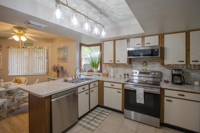 24 Mid Pines Cir Unit 24, Palm Coast, FL 32137 - kitchen featuring light countertops, a sink, a raised ceiling, a peninsula, and stainless steel appliances