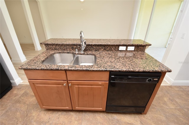 kitchen with dark stone counters, light tile flooring, a center island with sink, and dishwasher