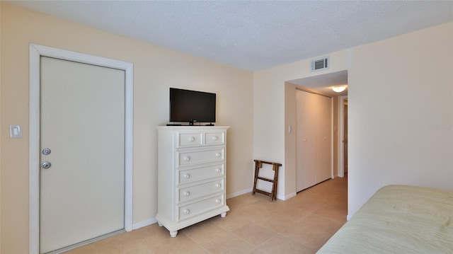 tiled bedroom with a closet and a textured ceiling