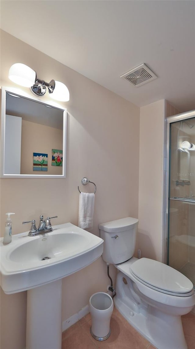 bathroom featuring a shower with door, tile flooring, and toilet