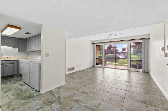 unfurnished room featuring tile floors, a textured ceiling, independent washer and dryer, and sink