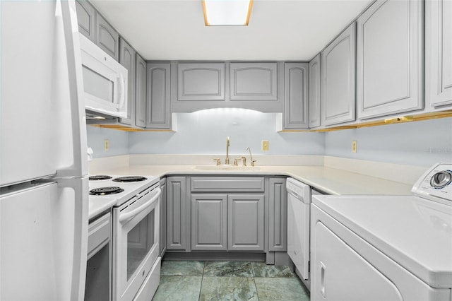 kitchen with gray cabinetry, white appliances, dark tile floors, washer / dryer, and sink