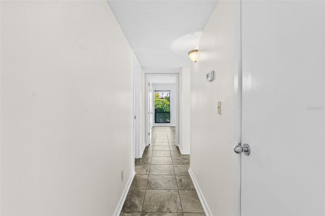 hallway featuring light tile floors and a textured ceiling