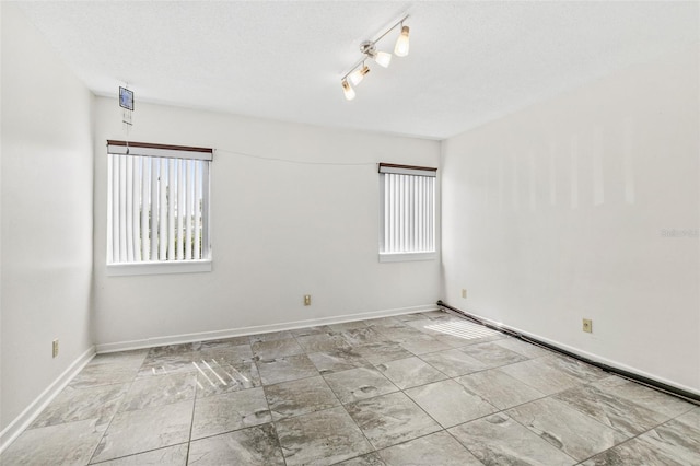 tiled spare room with plenty of natural light, rail lighting, and a textured ceiling