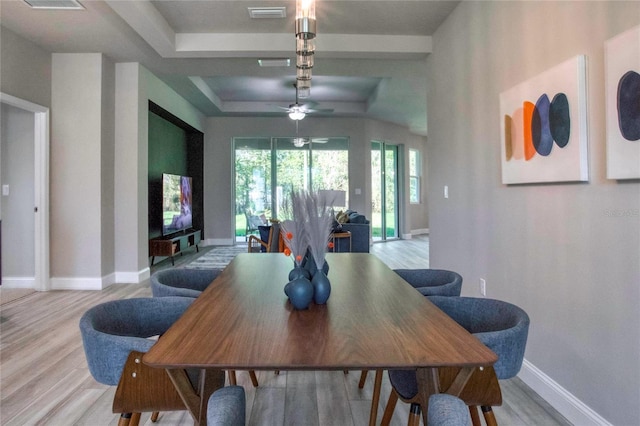 dining room with a raised ceiling, ceiling fan, and light hardwood / wood-style flooring