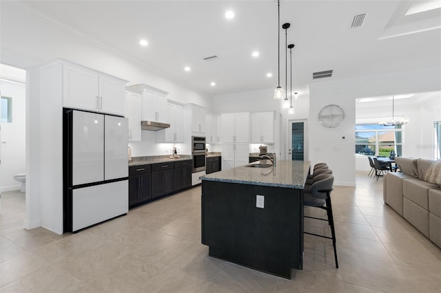 kitchen with high end fridge, white cabinetry, sink, and dark stone countertops