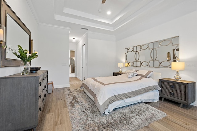 bedroom with ceiling fan, crown molding, light hardwood / wood-style flooring, and a raised ceiling