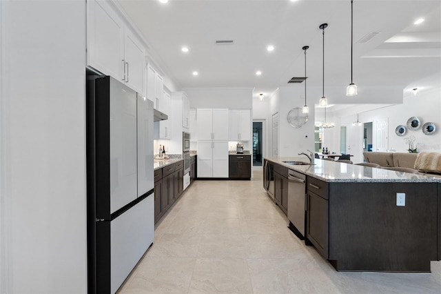 kitchen with an island with sink, pendant lighting, stainless steel appliances, white cabinets, and sink