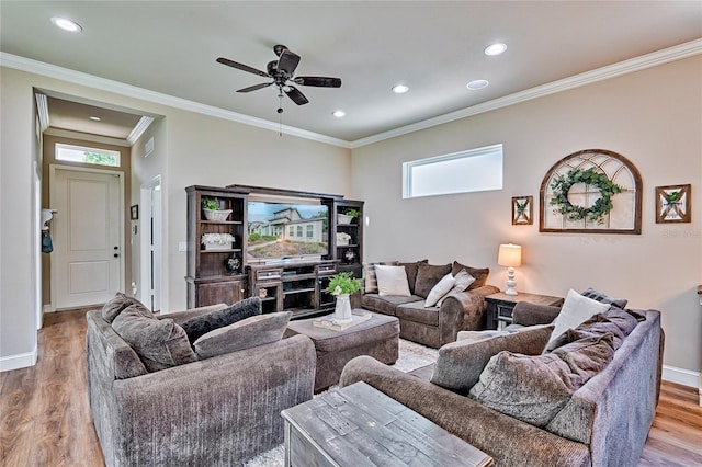 living room with ornamental molding, ceiling fan, a healthy amount of sunlight, and light wood-type flooring