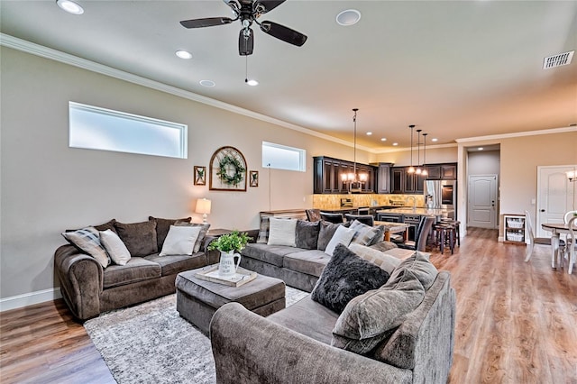 living room with light hardwood / wood-style floors, ornamental molding, and ceiling fan with notable chandelier